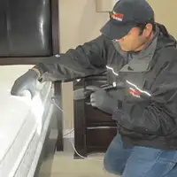 Bed bug inspection technician checking a mattress and bed frame for signs of infestation in Evansville, IN