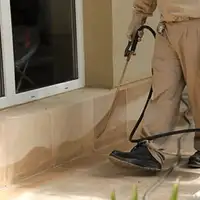 General pest control technician spraying exterior perimeter around a home in Evansville, IN