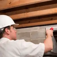 Termite inspection technician checking a basement wall and framing for termite activity in Evansville, IN